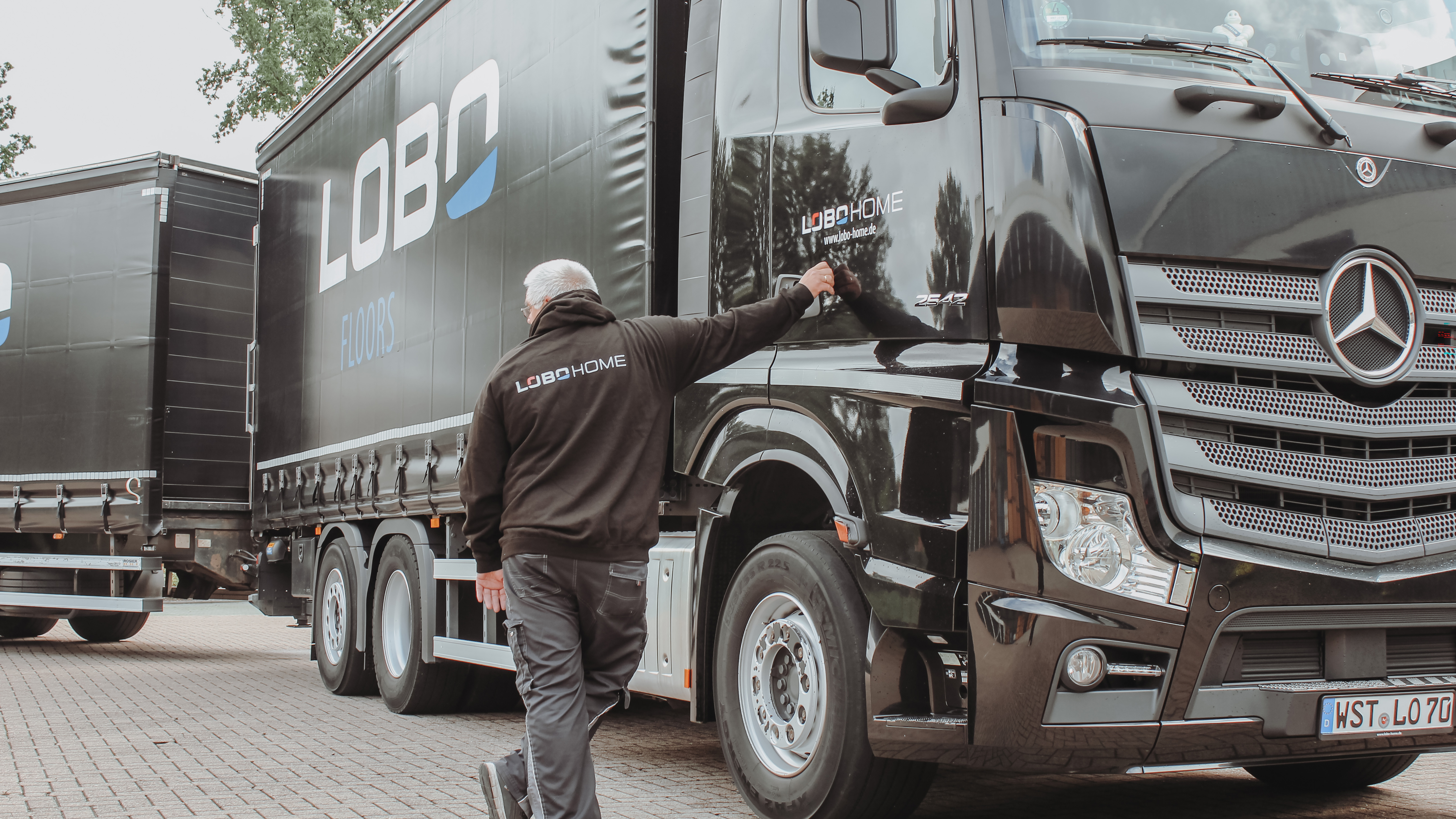 Mitarbeitender von LOBO HOME an einem gebrandeten Lkw auf dem Betriebsgelände