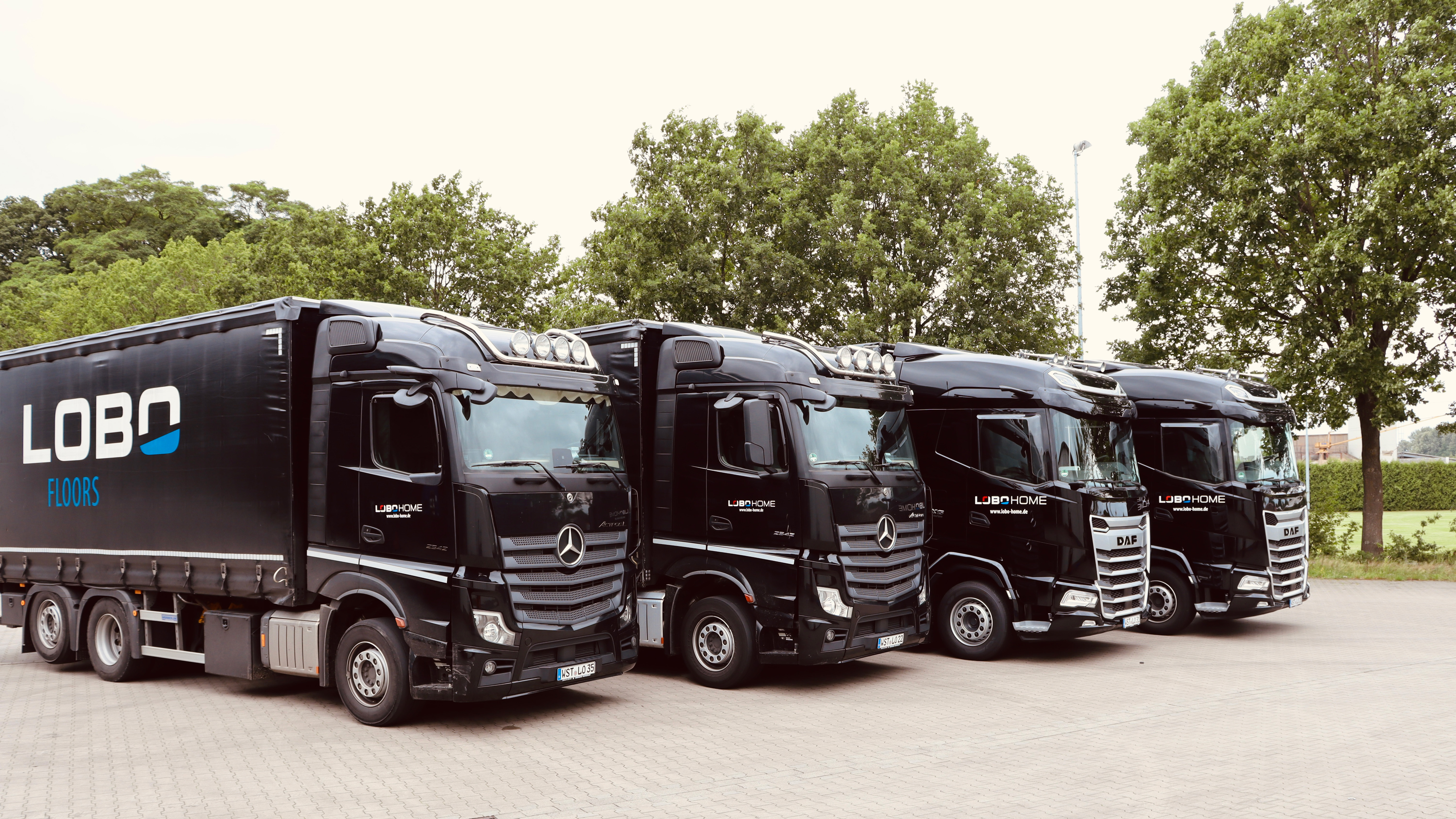 Mehrere schwarze LOBO HOME Lkw stehen nebeneinander auf dem Betriebsgelände
