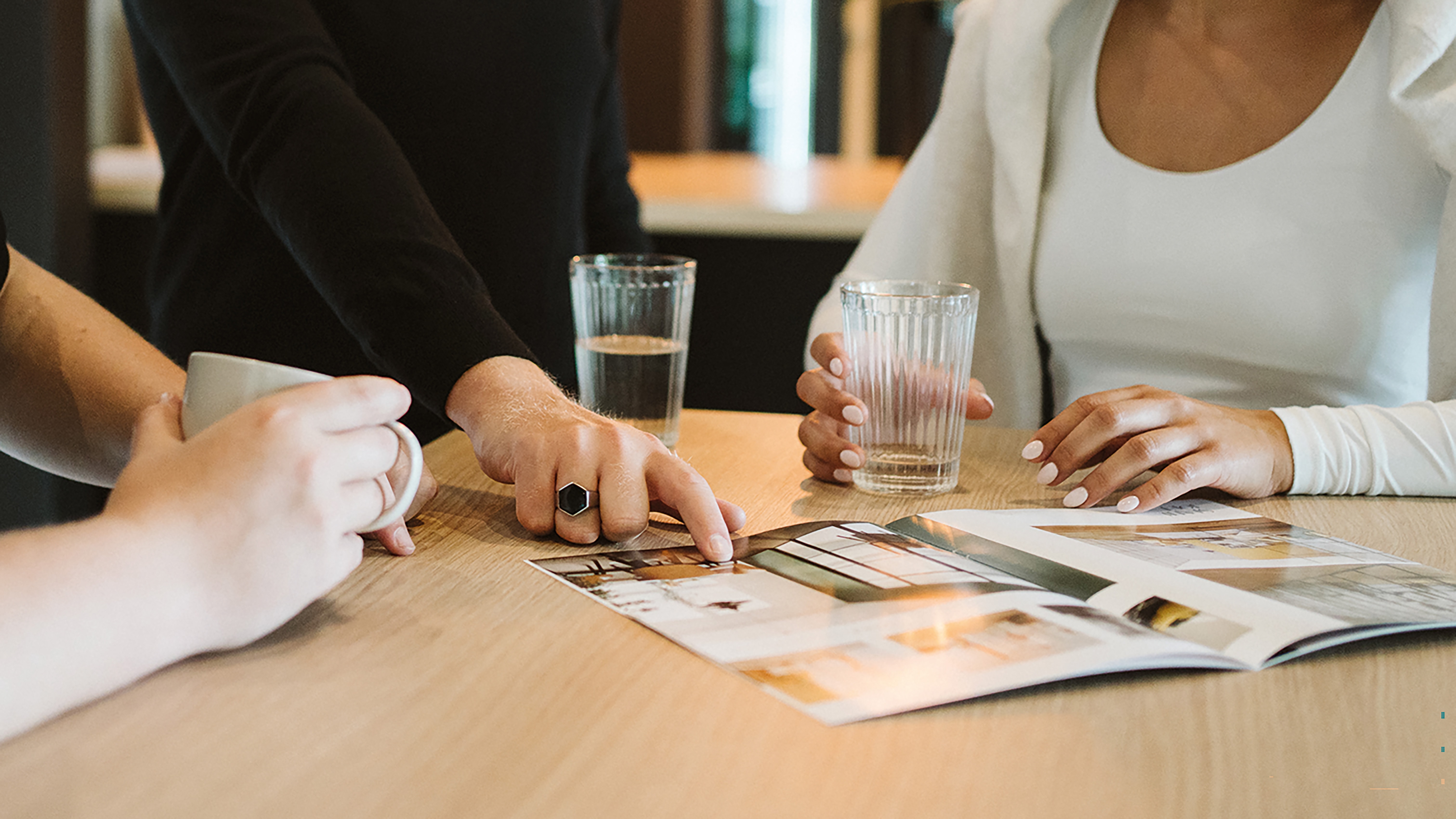 Personen besprechen Bildmaterial und Gestaltungsideen an einem Tisch