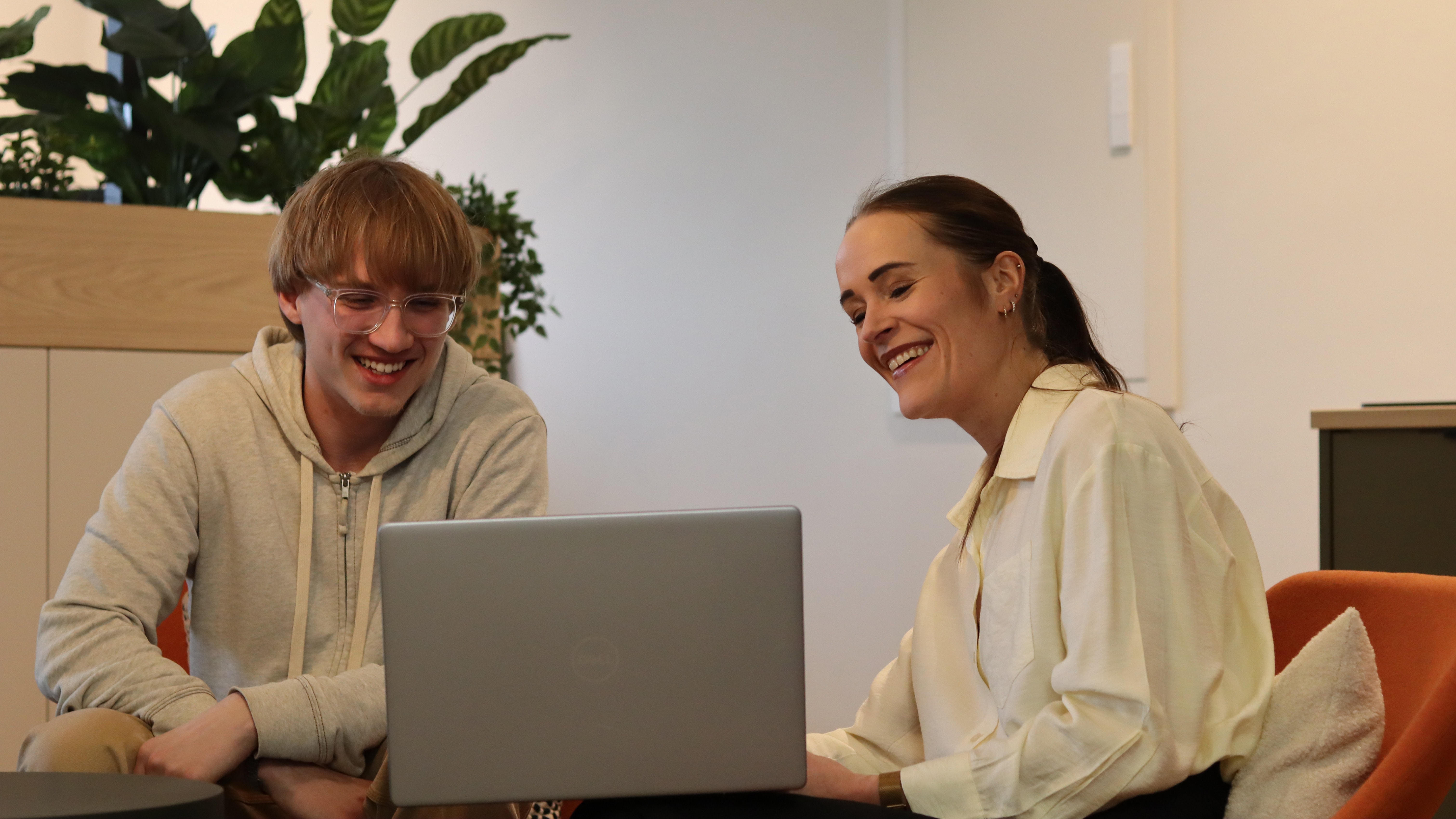 Zwei Personen arbeiten gemeinsam an einem Laptop in einem modernen Arbeitsbereich