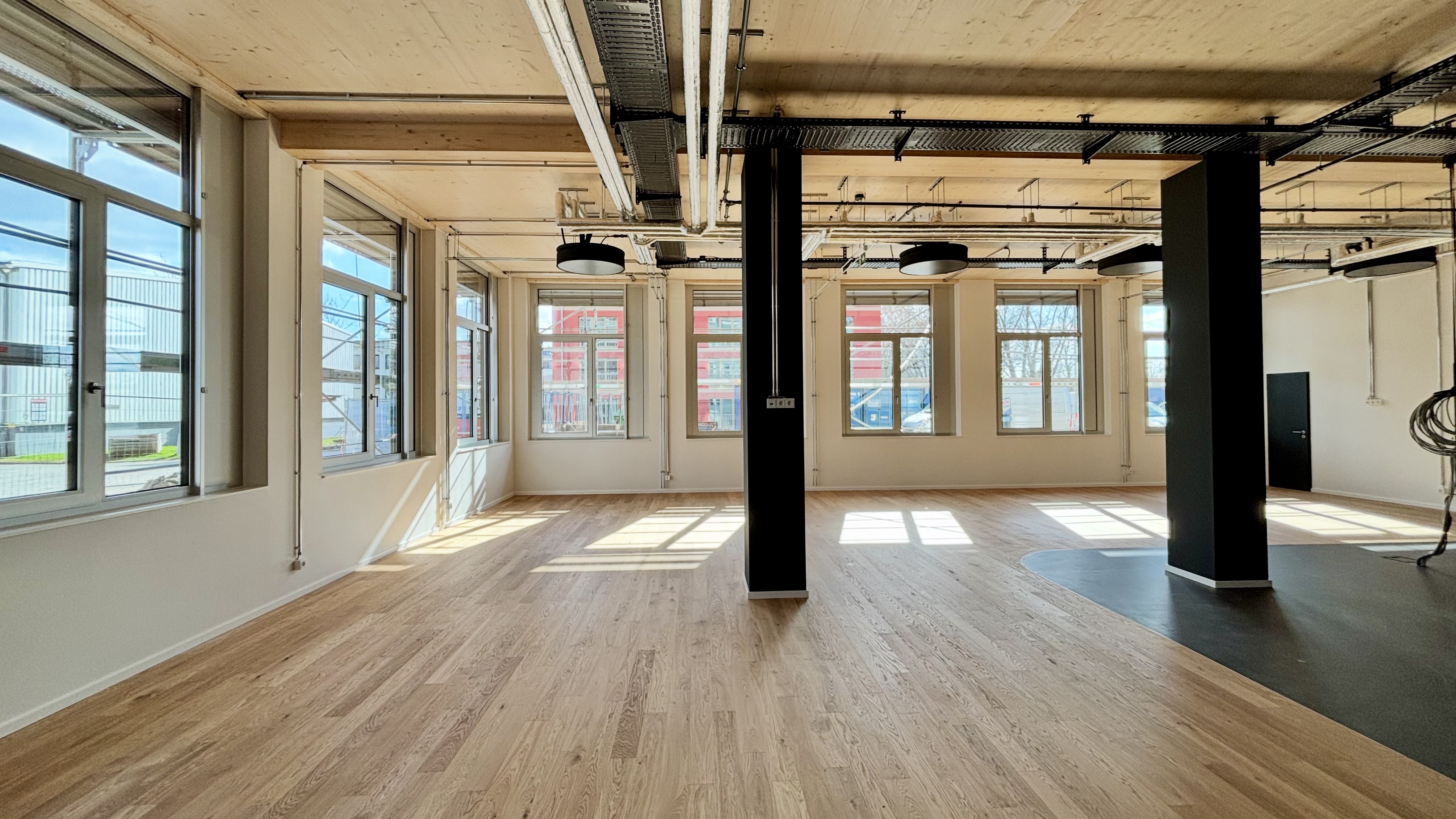 Helle Bürofläche im Lighthouse Bremen mit Holzoptik-Boden, großen Fenstern und sichtbarer Deckenkonstruktion