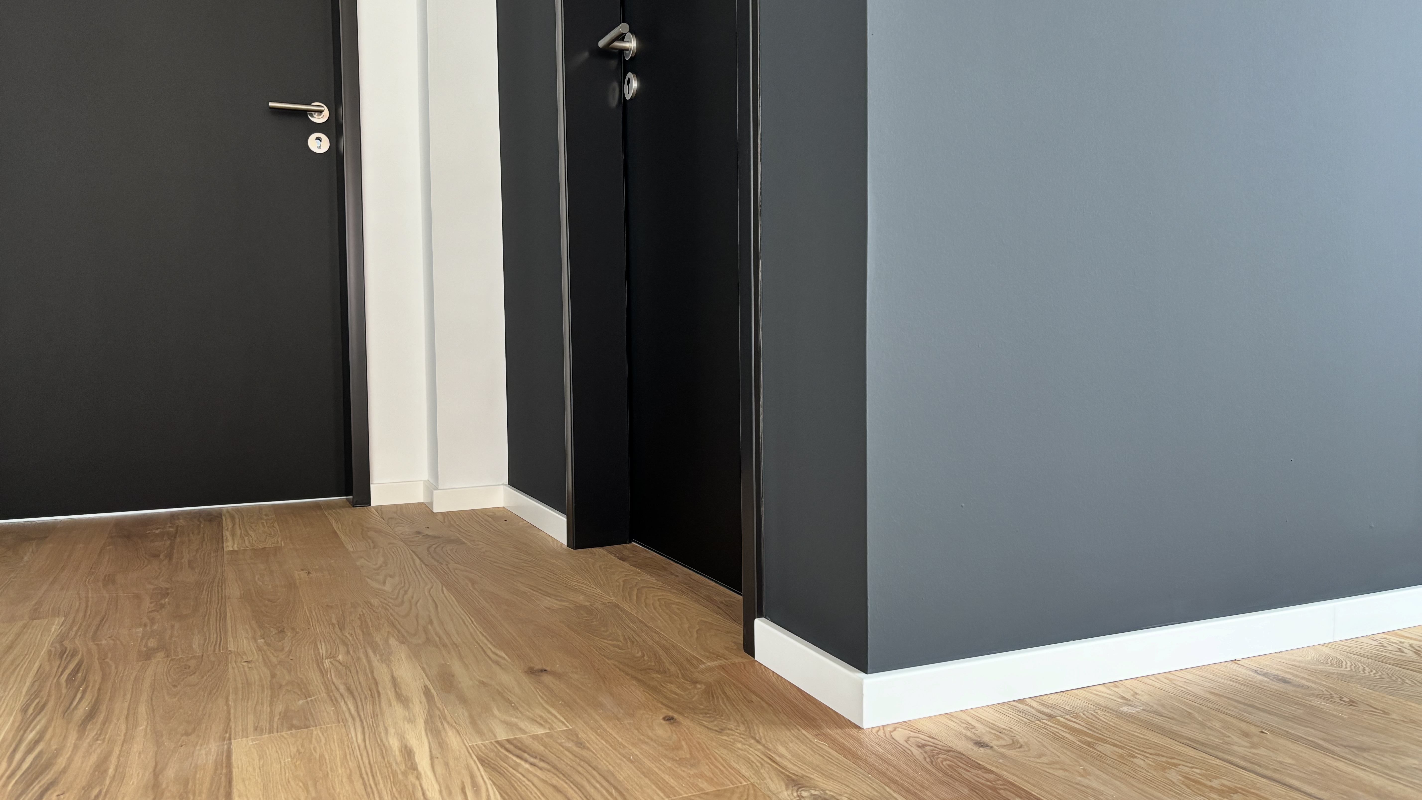 Detailaufnahme im Lighthouse Bremen mit schwarzen Innentüren, hellem Holzoptik-Boden und weißen Sockelleisten