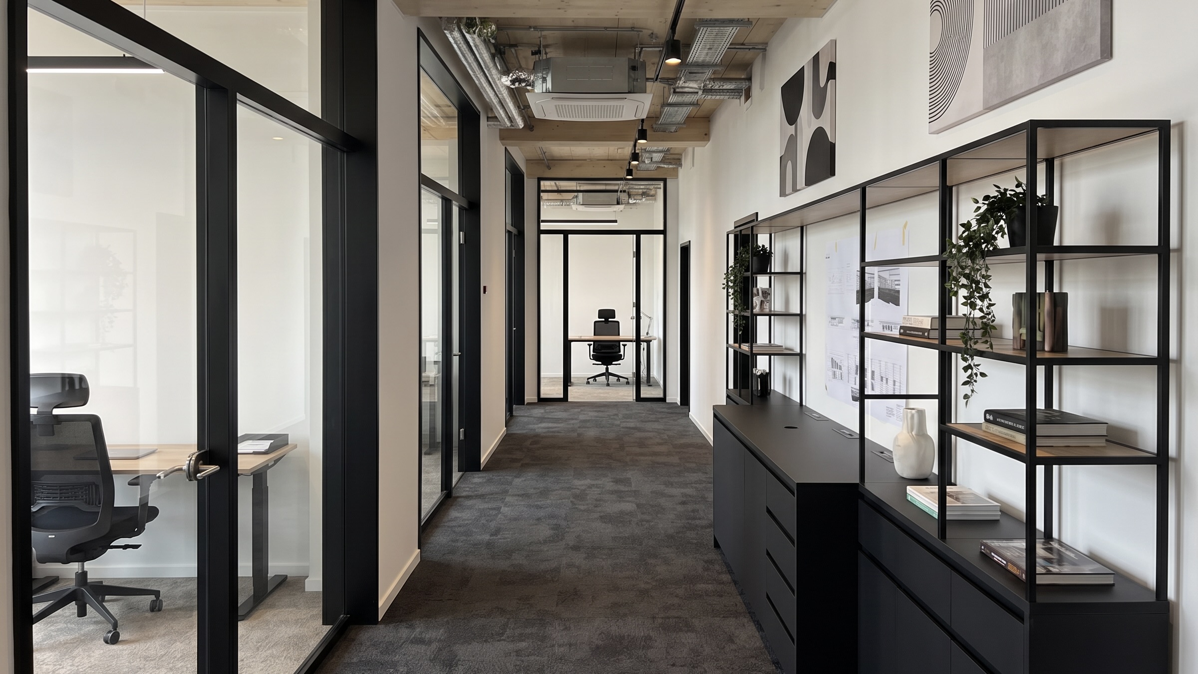 Moderner Bürobereich im Lighthouse Bremen mit schwarzen Glastrennwänden, Arbeitsplätzen und dunklem Boden