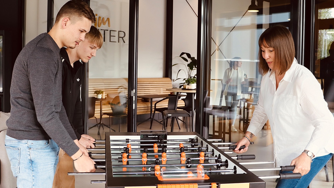 Mitarbeitende spielen Tischkicker in einem modernen Aufenthaltsbereich von LOBO HOME